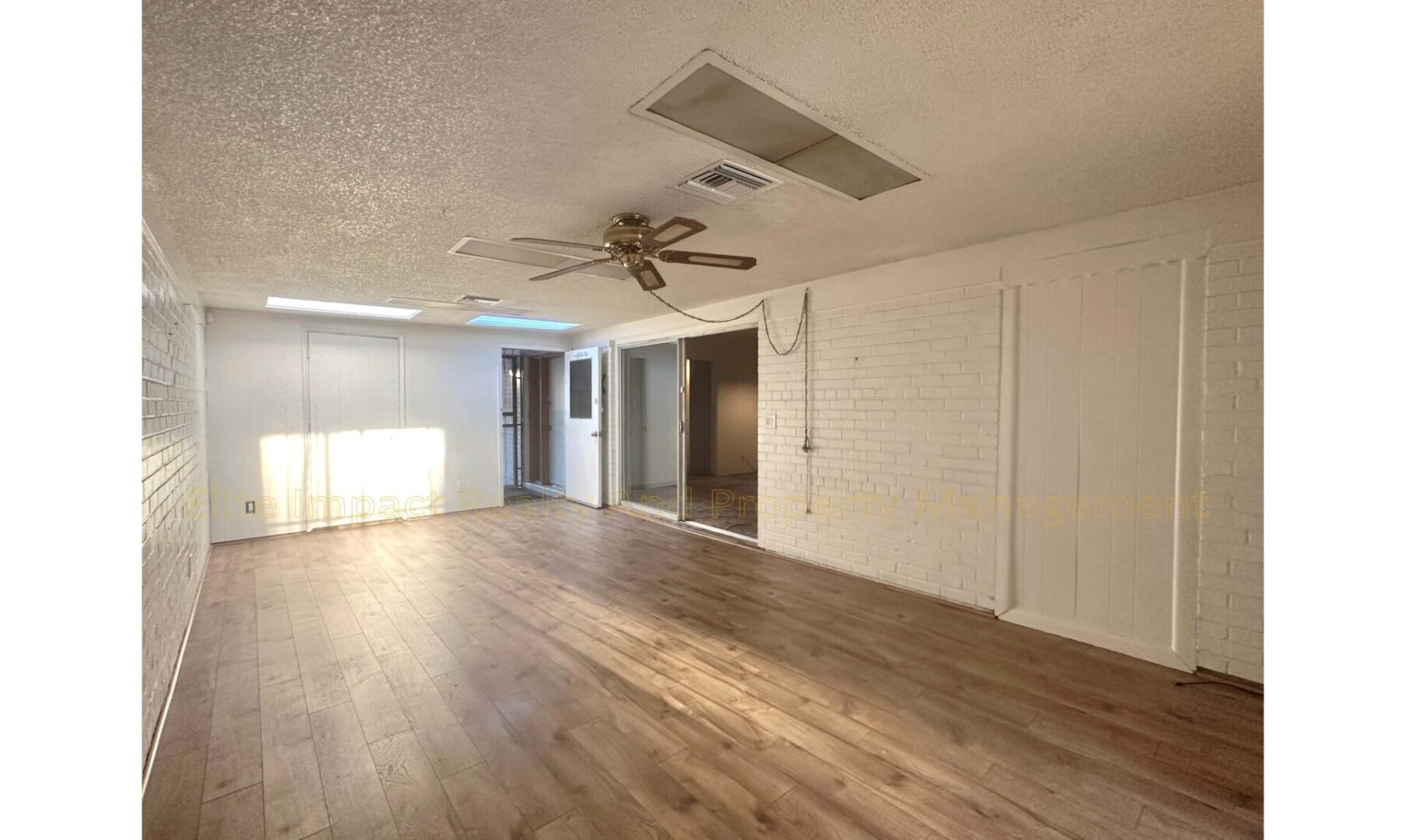 Empty living room with wood flooring and ceiling fan.