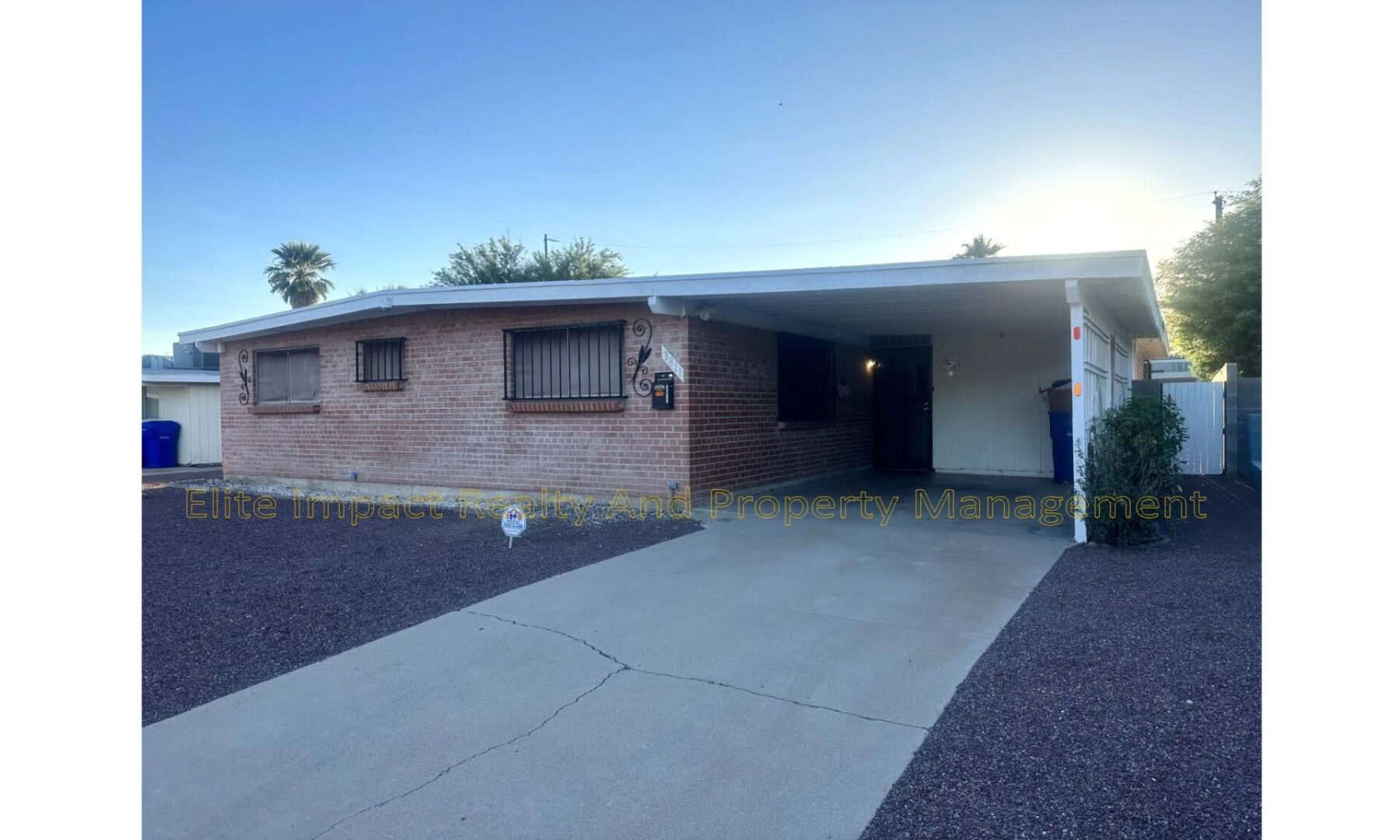 Single-story house with brick exterior and covered carport under a clear sky.
