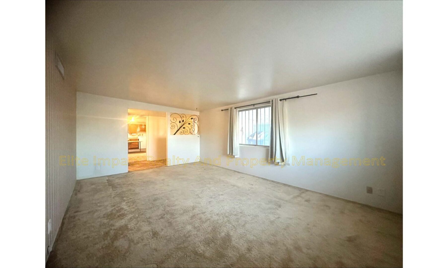 Empty beige-carpeted room with a large window and open doorway.