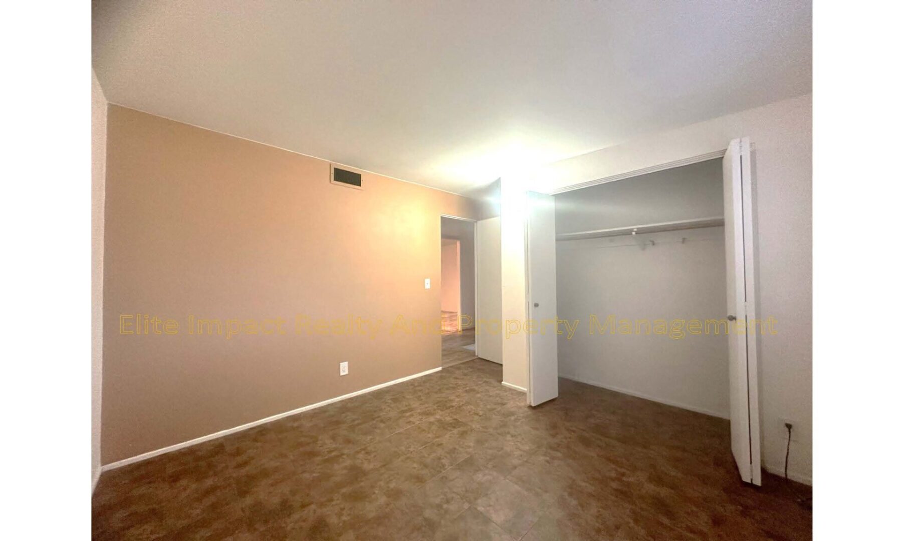 Empty living room with beige walls and brown carpet flooring.