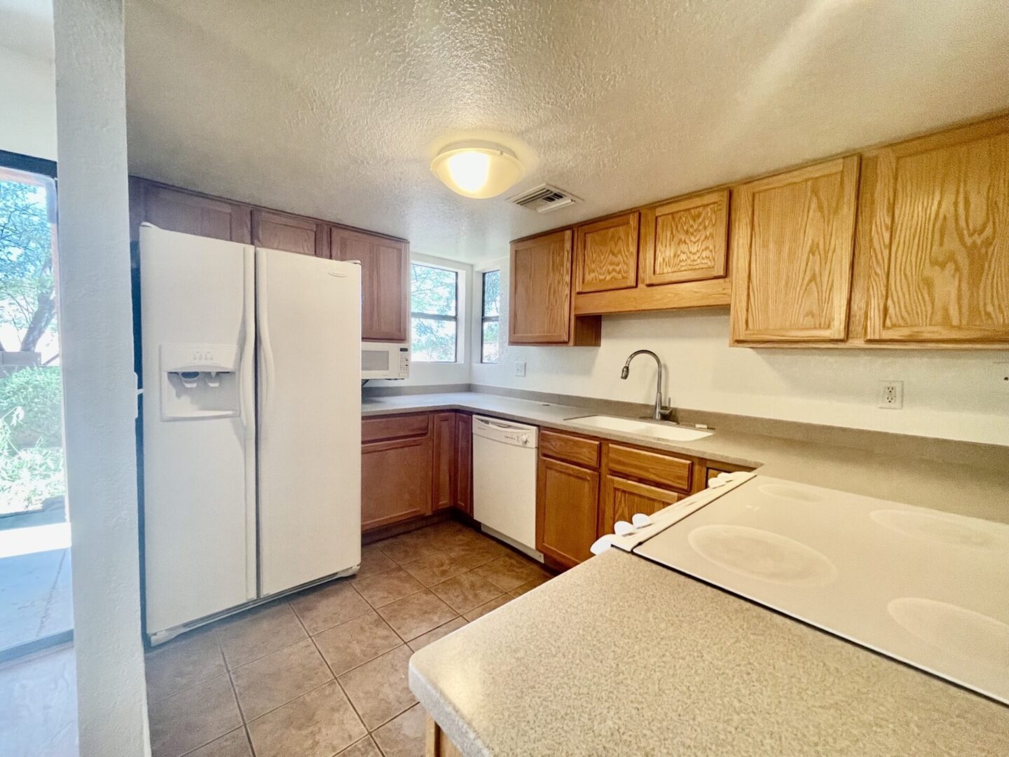 Bright kitchen with wooden cabinets and white appliances.