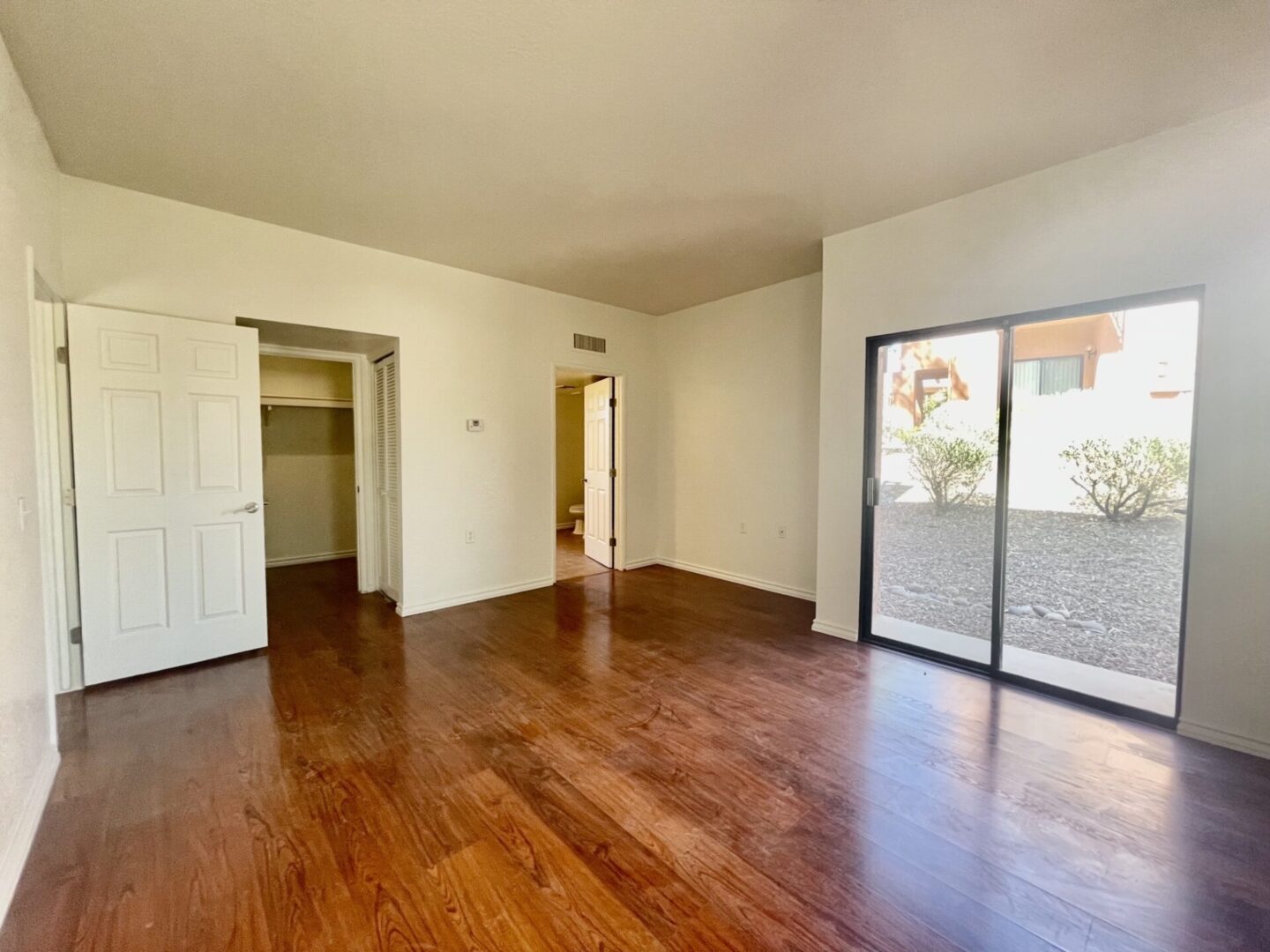 Empty room with wooden floor and sliding glass door.