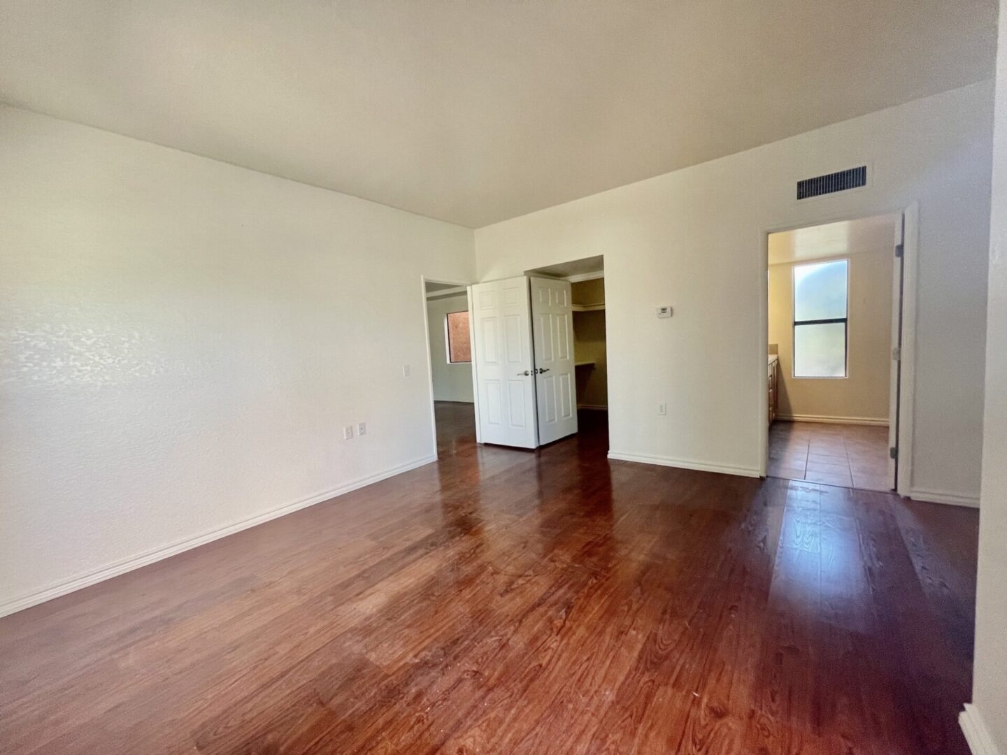 Empty room with wooden flooring and white walls.