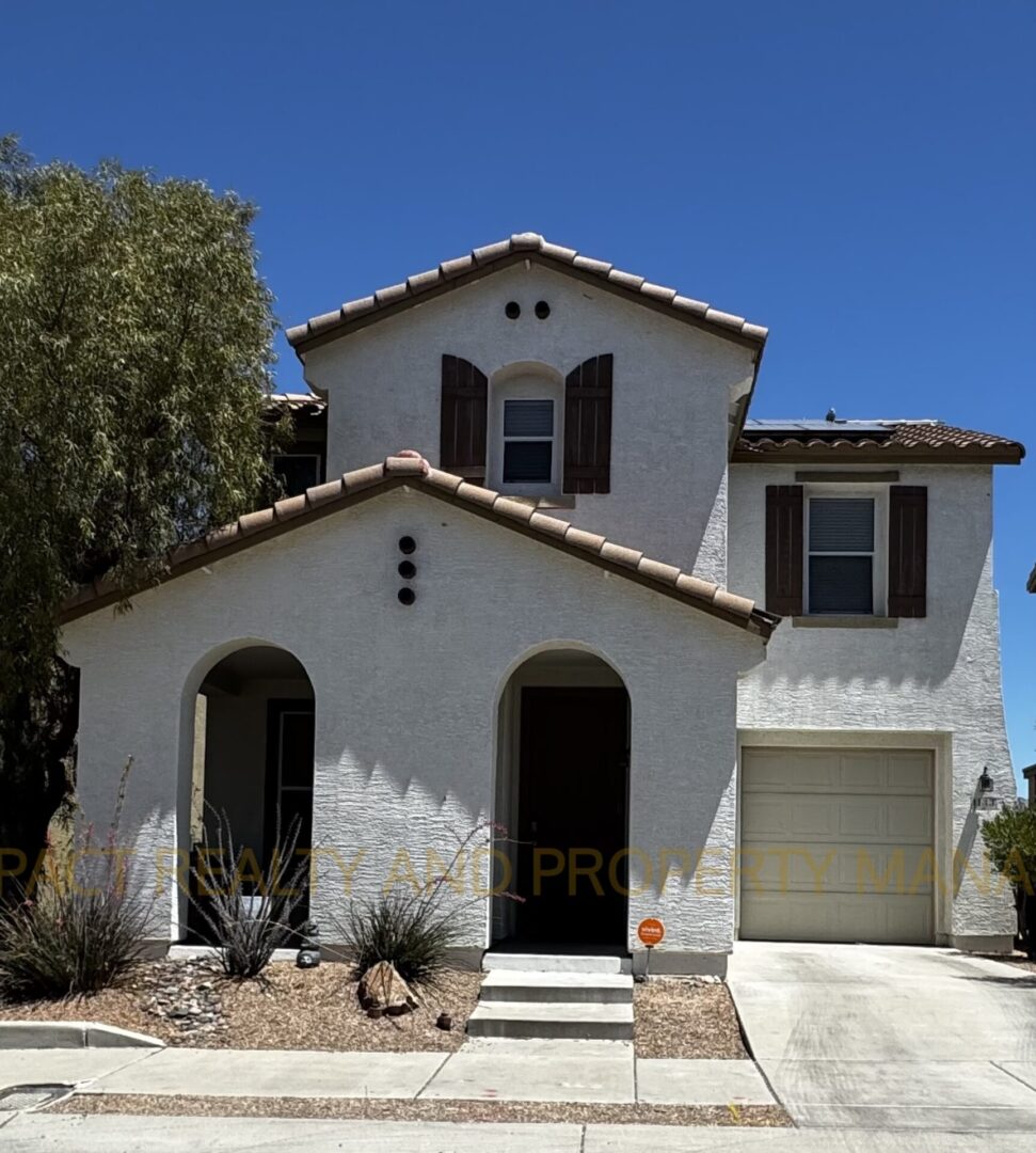 Two-story Mediterranean-style house with arched doorways and a small garage.