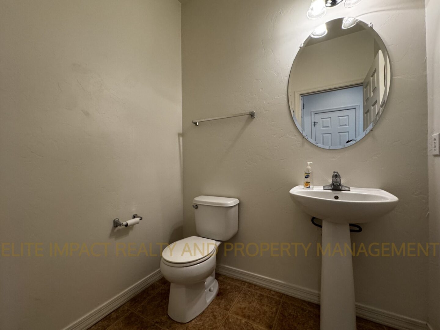 Small bathroom with toilet, pedestal sink, and oval mirror.
