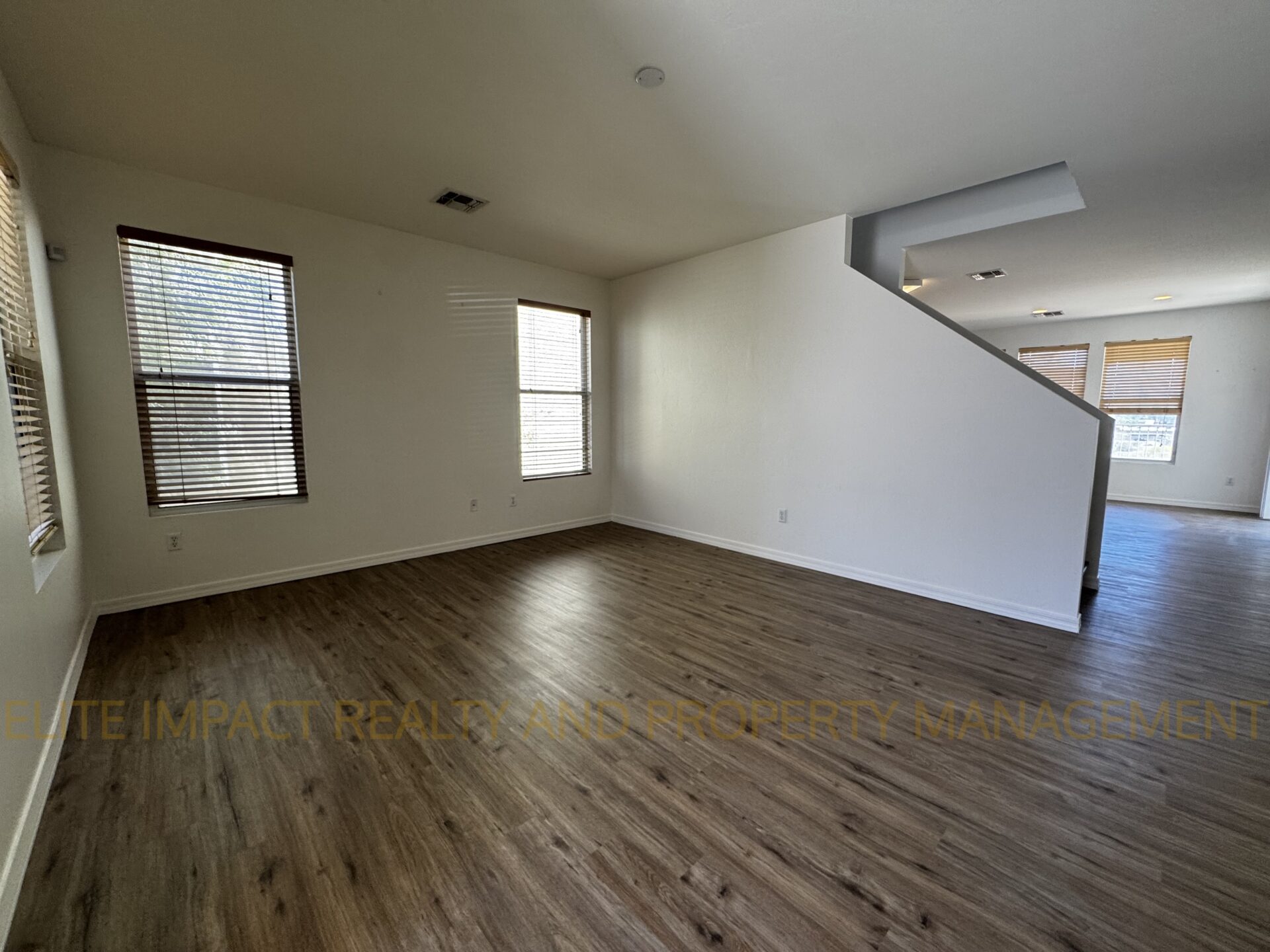 Empty room with wooden flooring and white walls.