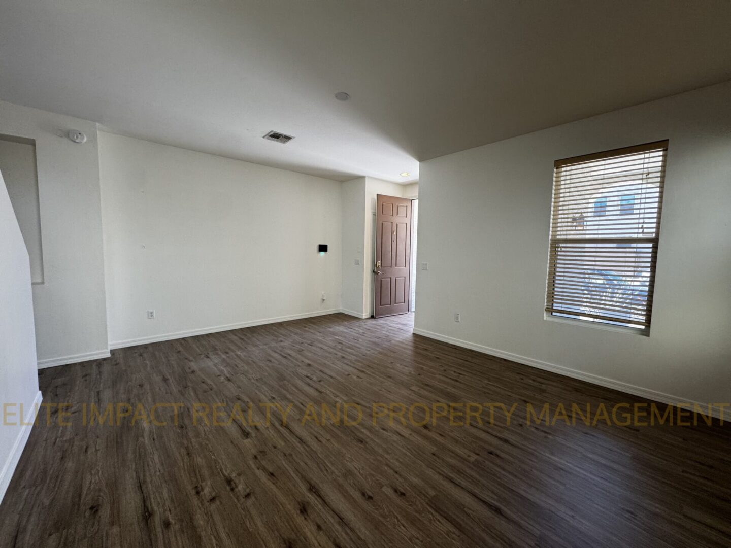 Empty room with wooden flooring and white walls.