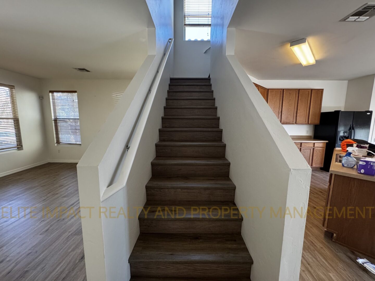 Wooden staircase with white railings leading to a bright upper floor.