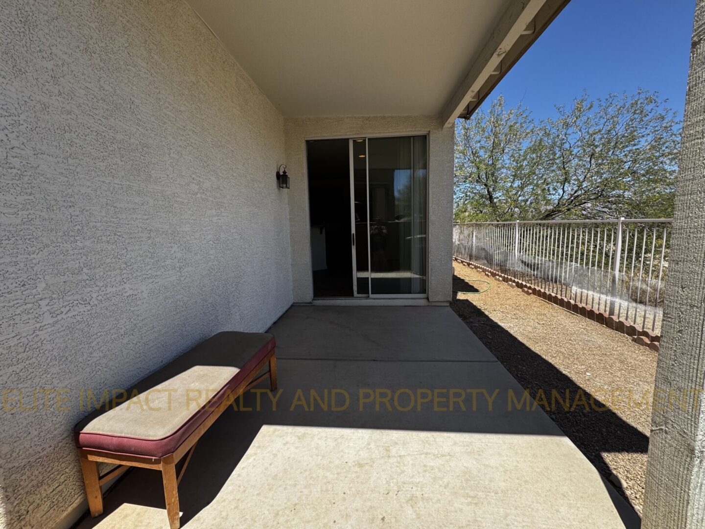 A small covered patio with a bench and sliding glass door.