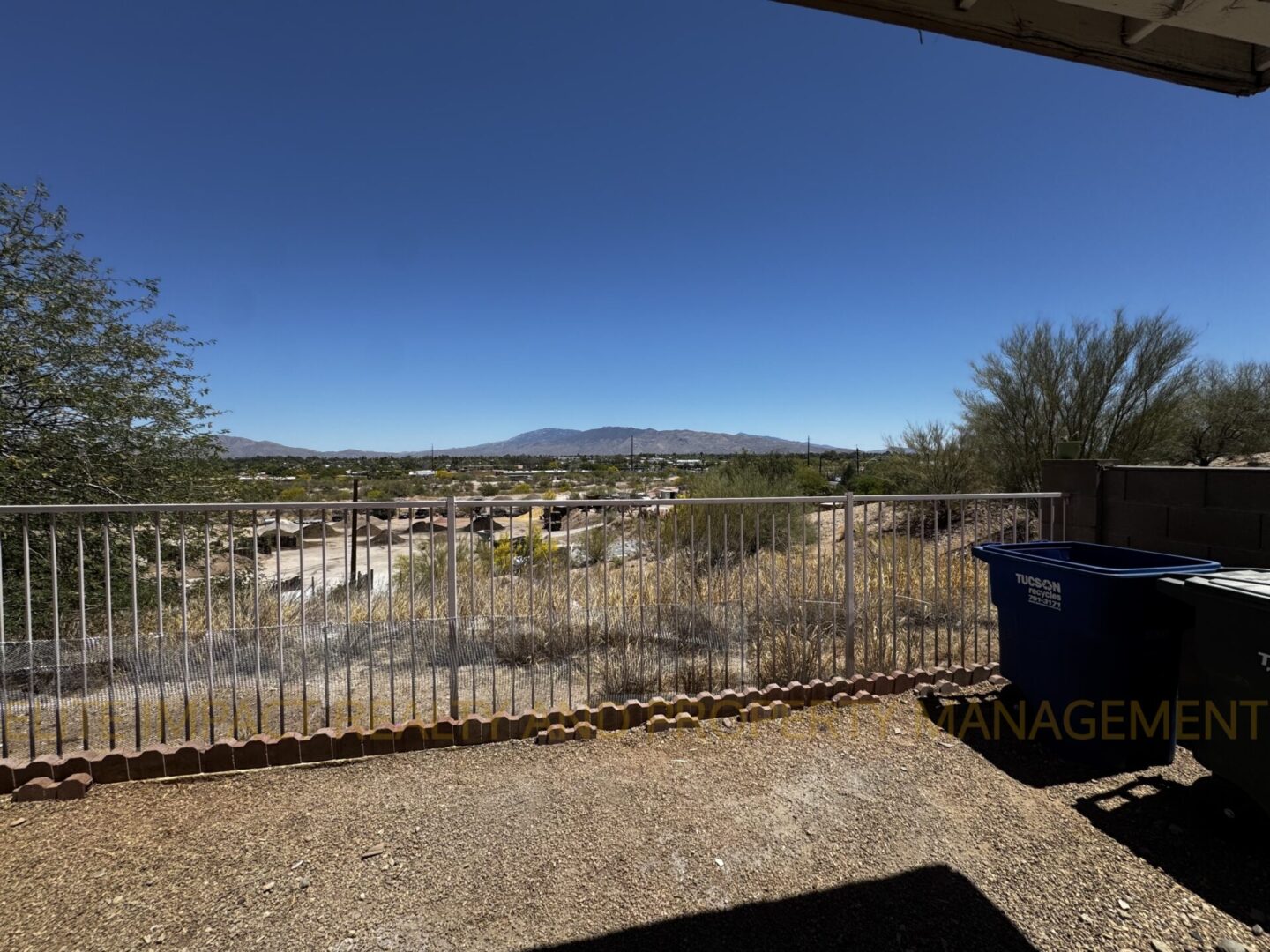 View of a dry riverbed under a clear blue sky with distant hills.