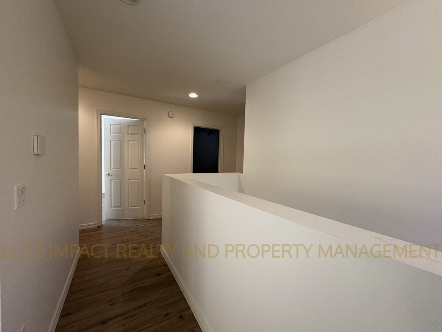 Minimalist hallway with wooden flooring and white walls.