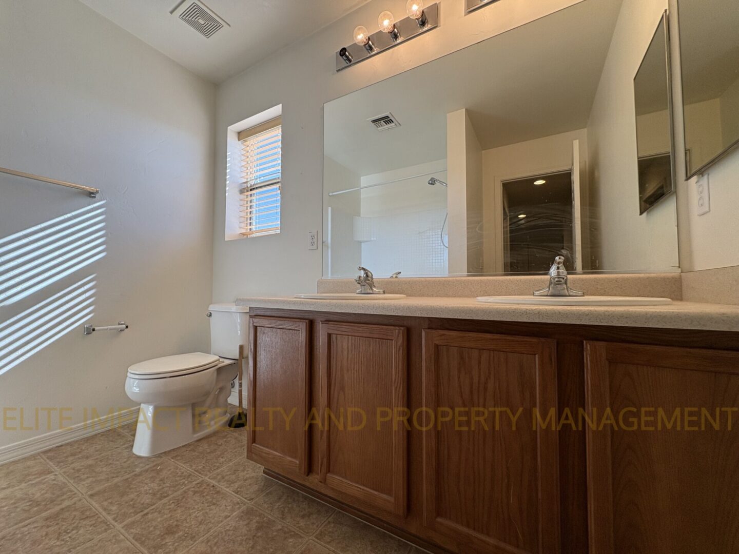 Bright bathroom with wooden cabinets and large mirror.